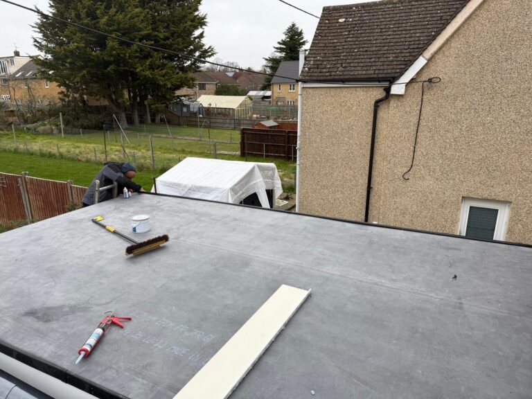 Flat roofing work beside a house with a tiled roof